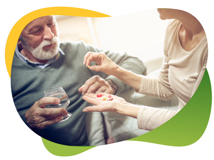 A woman hands over medicine to a man of retirement age who is is holding a glass of water