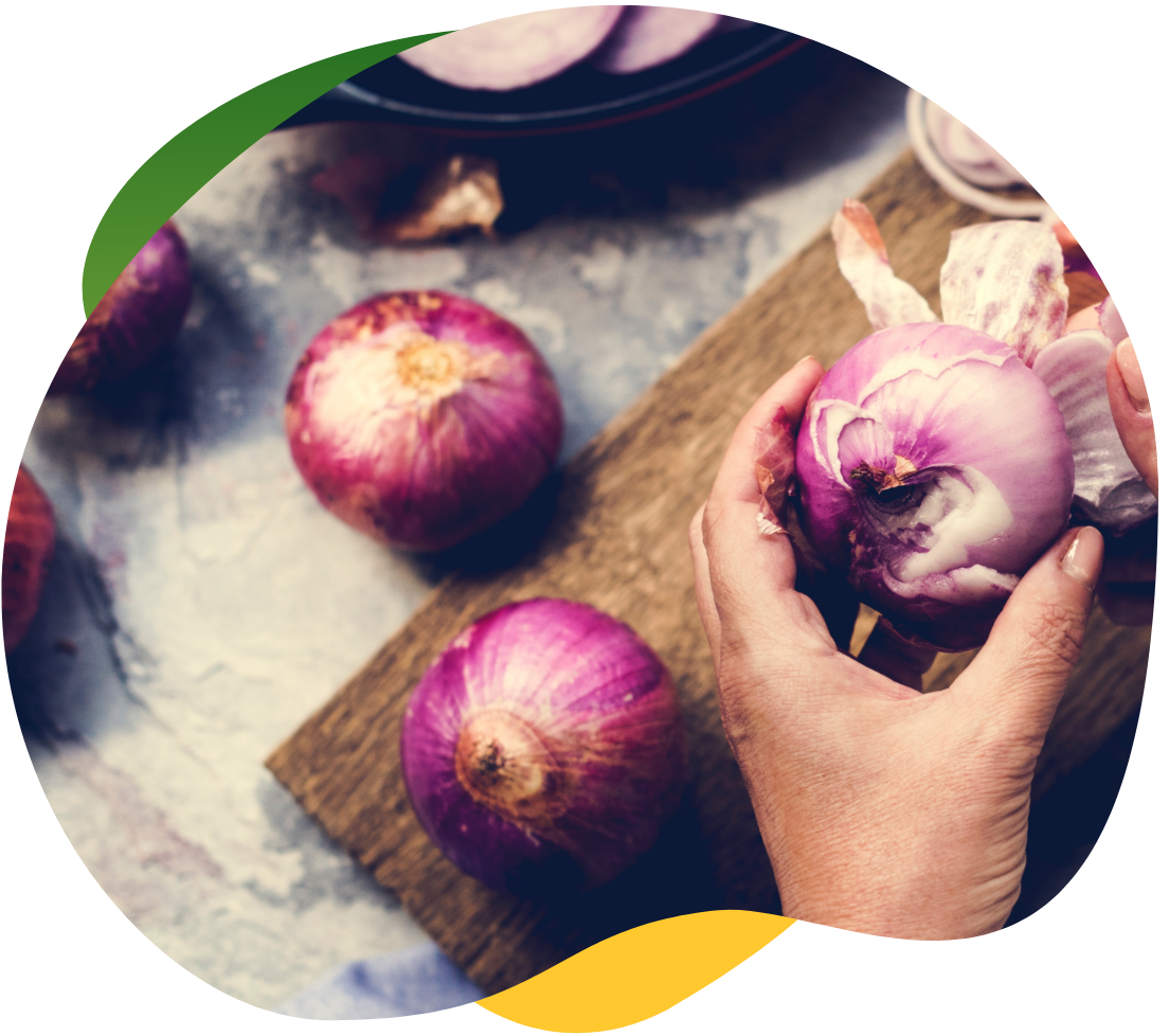 Hands peeling onions on a small board as onions contain fructans which can cause bloating.
